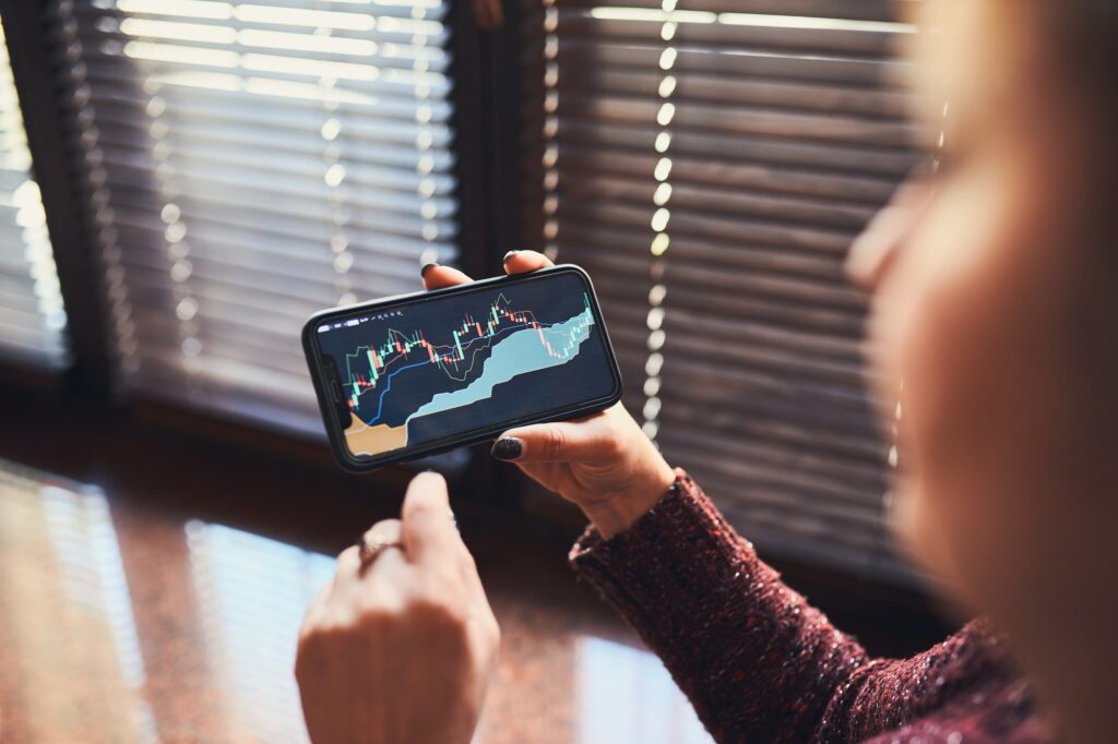 Woman investing trading on stock cryptocurrency market using investing application on smartphone