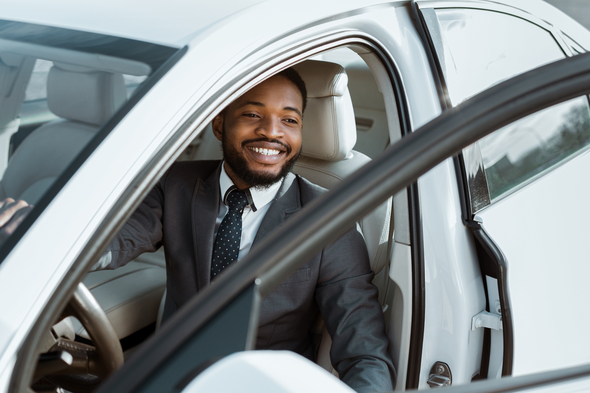 Smiling African American Businessman Entering White Sedan Car